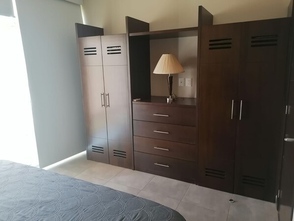 A bedroom with a bed, a wardrobe with multiple compartments, and a bedside table with a lamp.