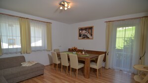Een eetgedeelte met een houten tafel, zes stoelen, een bank en een bijzettafeltje met een stoel.