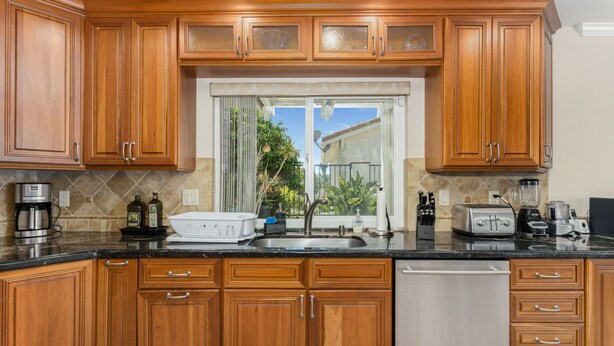 A kitchen with wooden cabinets, a dishwasher, a sink, and various appliances like a coffee maker and toaster.