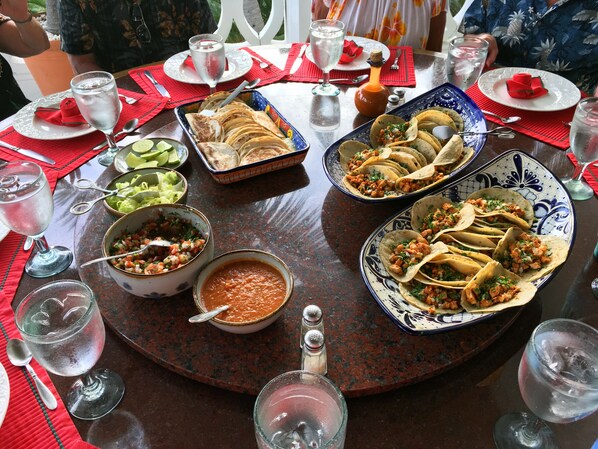 A dining table with various dishes, including tacos and a bowl of salsa.