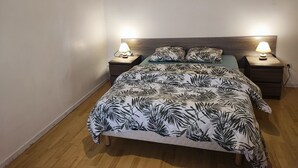 Un dormitorio con cama, dos mesitas de noche con lámparas, cabecero de madera y un adorno en la pared.