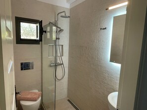 Un baño moderno con ducha envuelta en vidrio, inodoro y lavamanos.