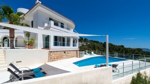 Una villa moderna con piscina, mobiliario de exterior y vistas panorámicas.