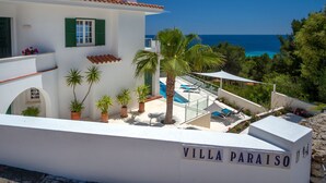 Villa Paraiso con piscina, contraventanas verdes y vista al mar.