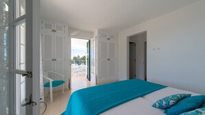 Un dormitorio con cama, una silla y vistas al exterior.