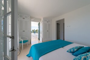 Un dormitorio con cama, una silla y vistas al exterior.