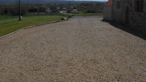 A gravel driveway leading to a stone building with a red-tiled roof. - Renovated house, close to beaches, pets allowed  (Plouégat-Guérand)