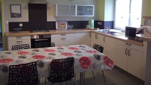 A kitchen with a dining table, chairs, a stove, a microwave, and a window. - Renovated house, close to beaches, pets allowed  (Plouégat-Guérand)