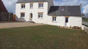 A two-story house with a white exterior, a grey roof, and a small attached garage. - Renovated house, close to beaches, pets allowed  (Plouégat-Guérand)