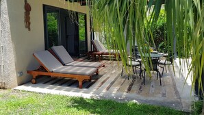 A covered outdoor seating area with lounge chairs and a table, surrounded by greenery. - Your own villa with private pool in tropical garden.  (Grand Baie)