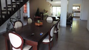 A dining area with a dark wooden table, white cushioned chairs, a small Christmas tree, and a bicycle in the background. - Your own villa with private pool in tropical garden.  (Grand Baie)
