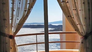 A room with a large window offering a view of a body of water and distant land. - Villa Stella,  swimming pool, by the beach,  close to Athens
 (Marathon)