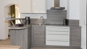 A modern kitchen with a curved island, white cabinetry, and a stainless steel range hood. - Attractive apartment between Munich, Tegernsee and Bad Tölz - free Wi-Fi (Sauerlach)