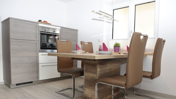 A modern kitchen with a built-in oven, a wooden dining table, and four chairs. - Attractive apartment between Munich, Tegernsee and Bad Tölz - free Wi-Fi (Sauerlach)