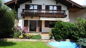 A two-story house with a balcony, a swimming pool, and a garden with flowers and shrubs. - Attractive apartment between Munich, Tegernsee and Bad Tölz - free Wi-Fi (Sauerlach)