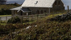 Ein Haus aus Stein mit einem geneigten Dach, einem Schornstein und einem kleinen Fenster.