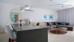 A modern living room with a dining area, a sofa, a coffee table, and a ceiling fan. - Luxury Condo, Roof Top Swimming Pool (Playa del Carmen)