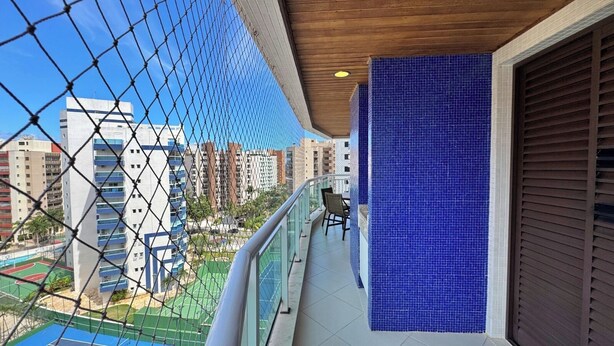 A balcony with a view of a tennis court and high-rise buildings.