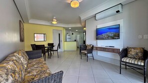 A living room with a sofa, chairs, a TV, and a dining area.