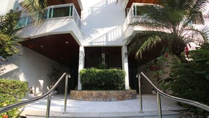 A multi-level building with a stone staircase, metal railings, and a small garden area with plants and a palm tree.