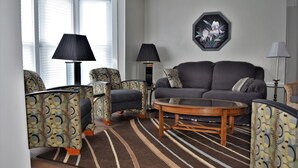 Ein Wohnzimmer mit gestreiften Sesseln, einer Couch, einem Couchtisch und zwei Lampen.