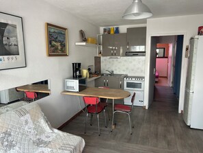 A compact kitchen with a dining area, a refrigerator, a stove, and a microwave.