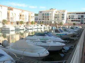 A marina with several boats docked, surrounded by buildings with arched windows and balconies. - 2026 season for a 32 m² two-bedroom apartment + terrace and parking near the beaches (Sète)