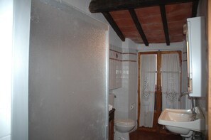 Une salle de bain comprenant des toilettes, un lavabo et un espace douche.