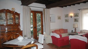 A cozy living room with a wooden cabinet, a dining table with chairs, a red sofa, and a white armchair. - Ancient country house recently restored - beautiful private garden - panoramic (Pontassieve)