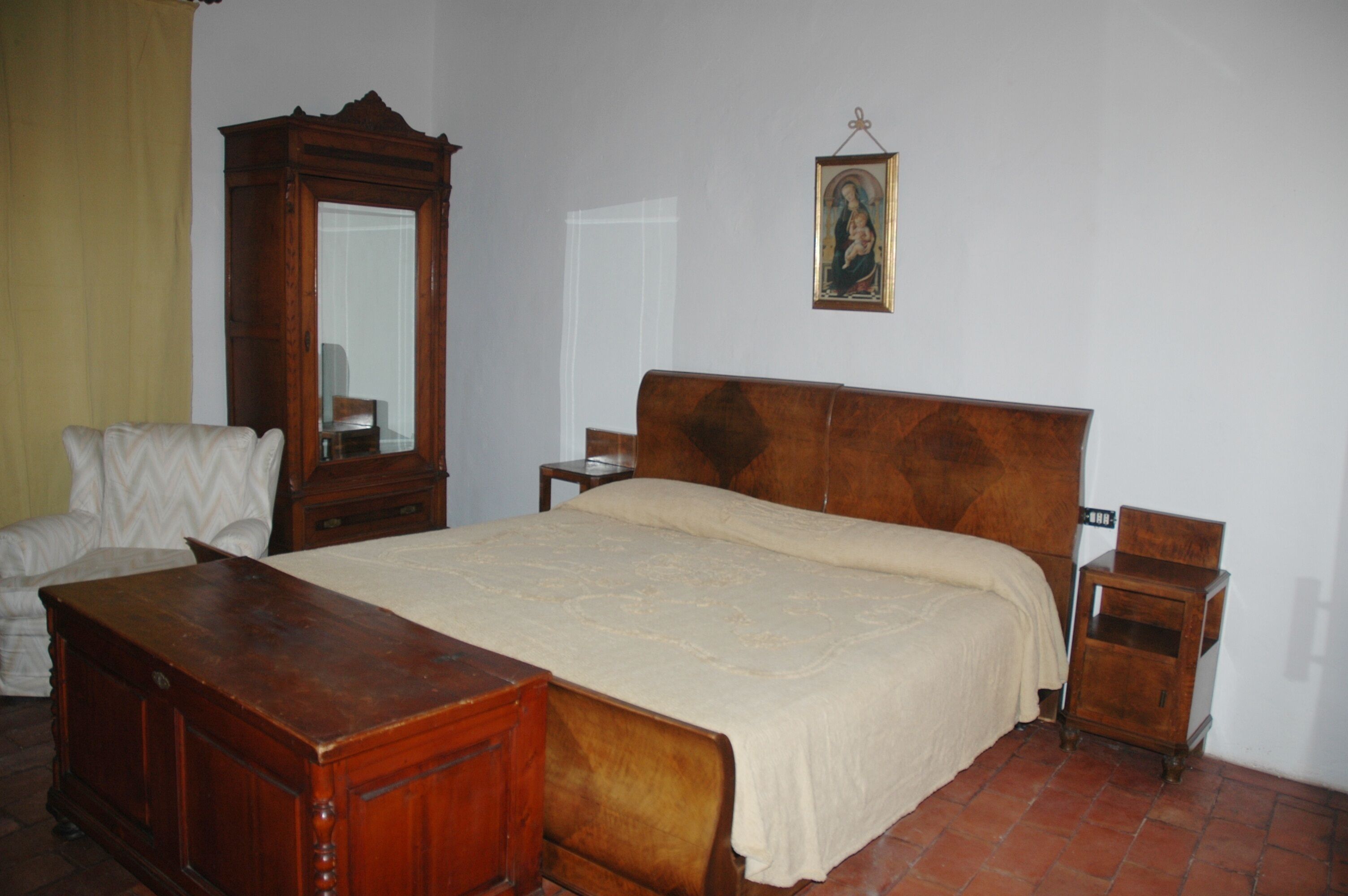 Un dormitorio con cama de madera, cómoda de madera, una silla y una mesita de noche.