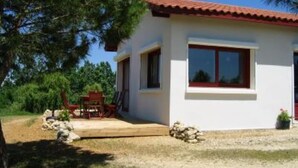 A single-story house with a red-tiled roof, a front porch with a red chair, and a small garden area with rocks and a potted plant. - Lots of charm for this house 3 ears, brand new, with its unparalleled panoramic view (Courrensan)
