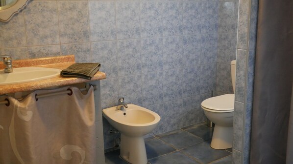 A bathroom with a sink, bidet, and toilet.