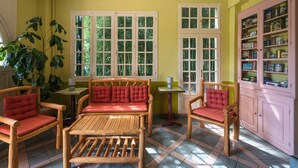 A room with a wooden sofa, two armchairs, a small table, and a cabinet with glass doors.