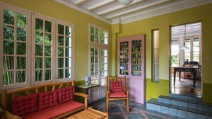 A room with a wooden bench, a red cushioned sofa, a wooden chair, and a cabinet with glass doors.
