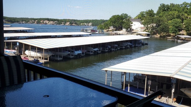 Une vue depuis un balcon donnant sur une marina où des bateaux sont amarrés sous des abris.