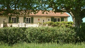 Una casa tradizionale con tetto in tegole rosse, persiane verdi e facciata bianca.