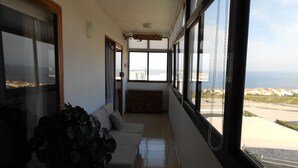 Una habitación con sofá, una planta en maceta y vista al mar a través de amplios ventanales.