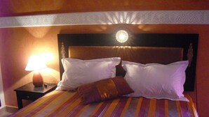 Ein Bett mit gestreifter Bettwäsche, ein Nachttisch mit Lampe und ein dekoratives Kopfteil.