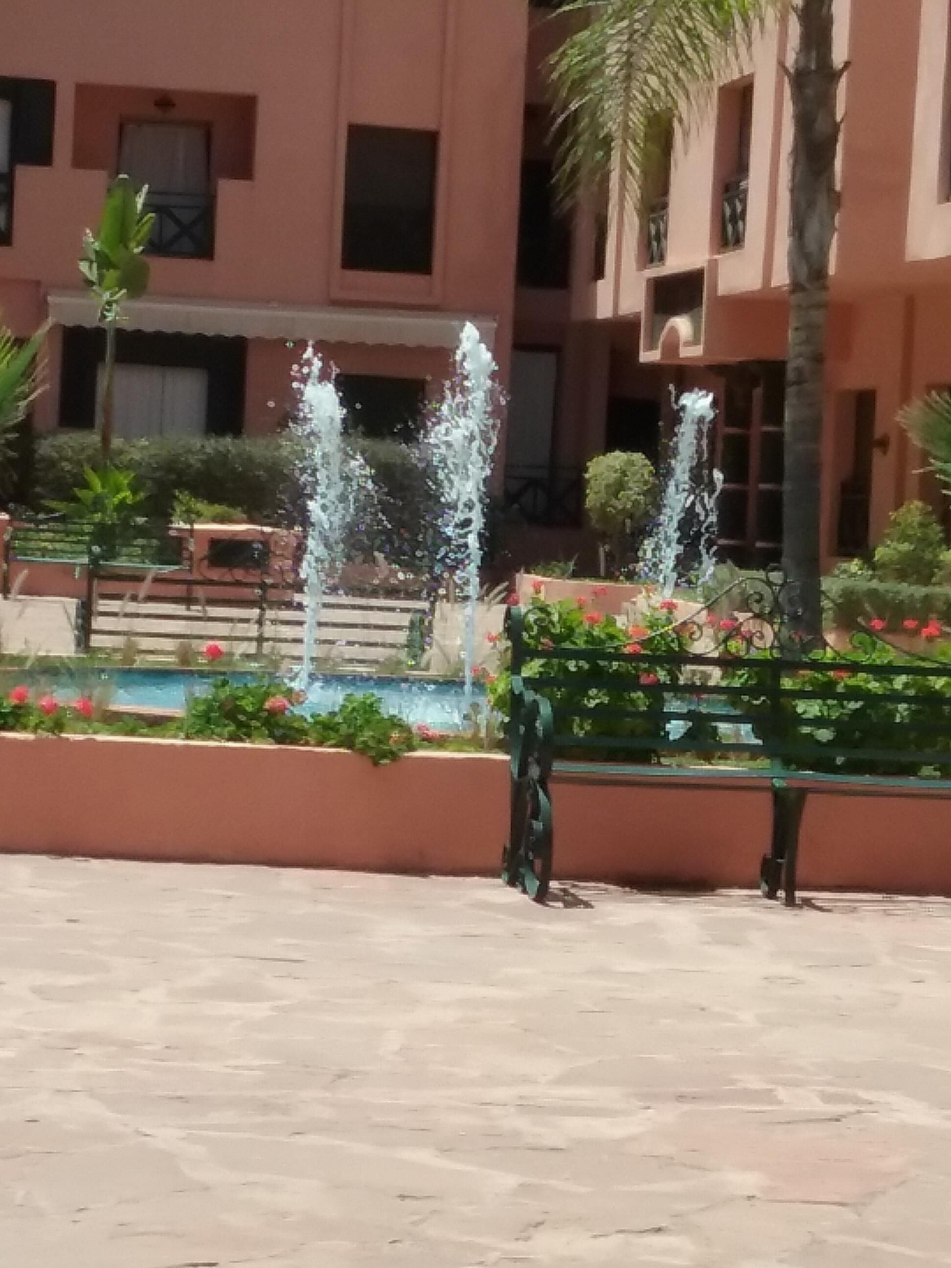 A courtyard with a fountain, a pool, and a bench.