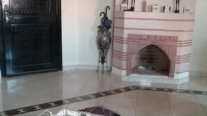 Ein Zimmer mit einer schwarzen Tür, einem Kamin mit Dekorationen und einem Tablett mit Fernbedienungen auf einem Tisch.
