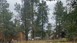 Un espacio al aire libre con sillas Adirondack y un brasero, rodeado por un borde de piedra y guijarros.