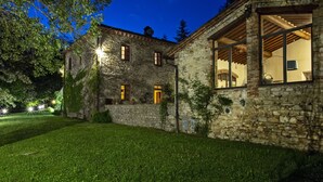 Une maison en pierre avec une pelouse bien entretenue, de grandes fenêtres et une porte bien visible.