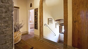 Un couloir avec une porte en bois, un mur en briques et un escalier menant à une autre pièce.