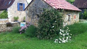 A stone house with a red-tiled roof, surrounded by lush greenery and flowering plants. - La Boissière: Peaceful vacations in Périgord Noir (Saint Chamassy)
