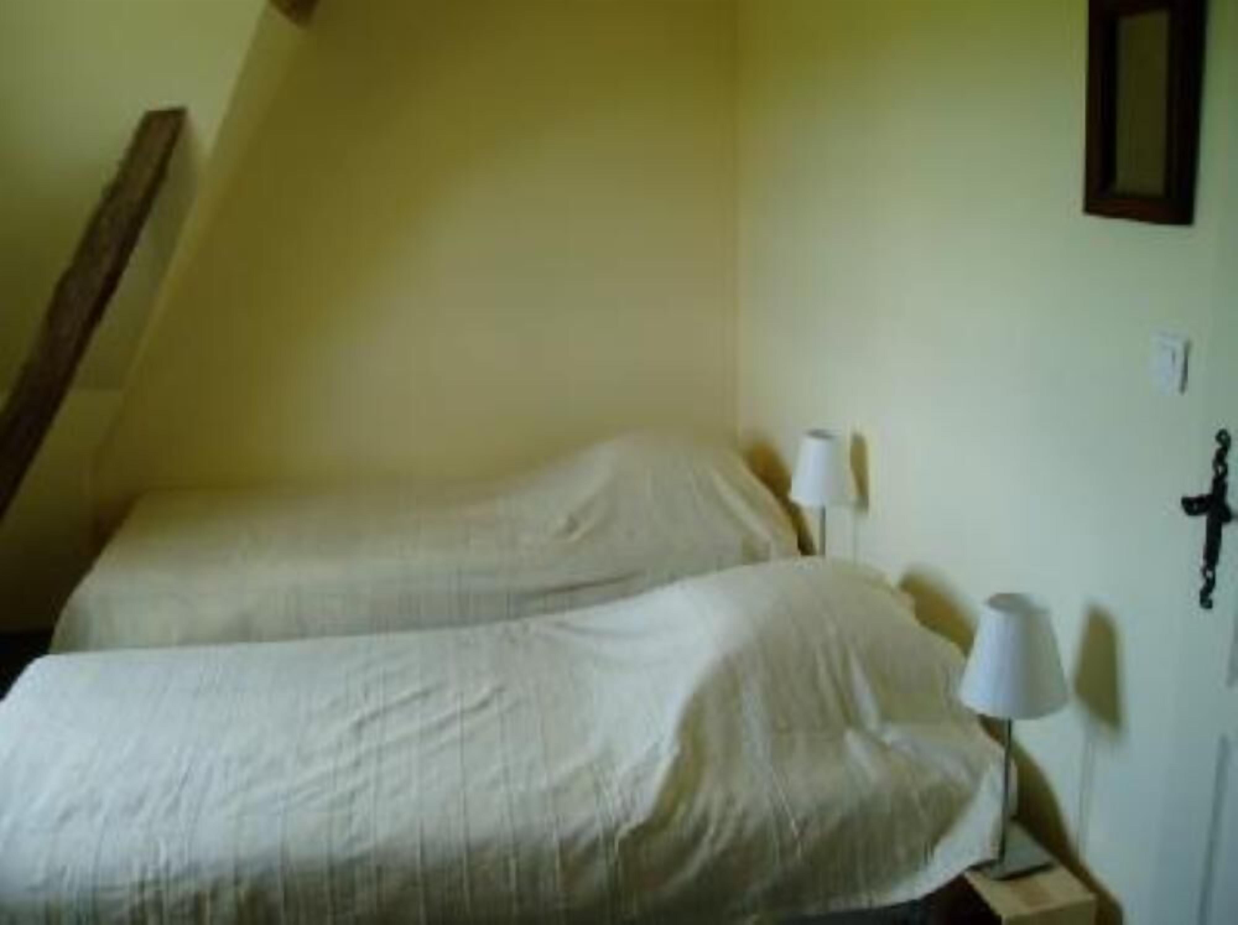 A small, single-bed room with a sloped ceiling and a simple bedside table with a lamp.