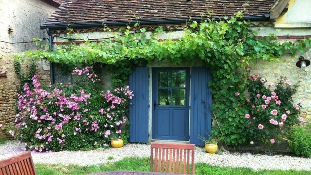 A rustic stone building with a blue door, surrounded by lush greenery and pink flowers. - La Boissière: Peaceful vacations in Périgord Noir (Saint Chamassy)