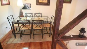 A dining area with a glass table and metal chairs, wooden beams, and framed artwork on the walls. - Apartment/ flat - Lisboa (Lisboa)