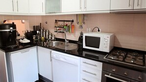 A modern kitchen with white cabinets, a black countertop, a microwave, a stove, and a dishwasher. - Apartment/ flat - Lisboa (Lisboa)