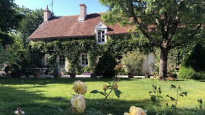 A house with a red-tiled roof, surrounded by a well-maintained garden with roses and trees. - Beautiful cottage with pool , LOIRE VALLEY close to ORLEANS .1 hour from Paris . (Saint-Jean-De-Braye)