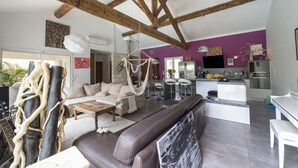 Een ruime woonkamer met hoge plafonds, een moderne keuken en een eethoek.